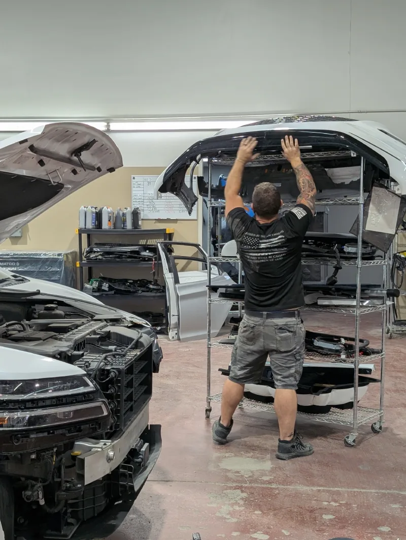 McCarthy Collision Center: A truck with its hood open and a technician grabbing parts from a shelf