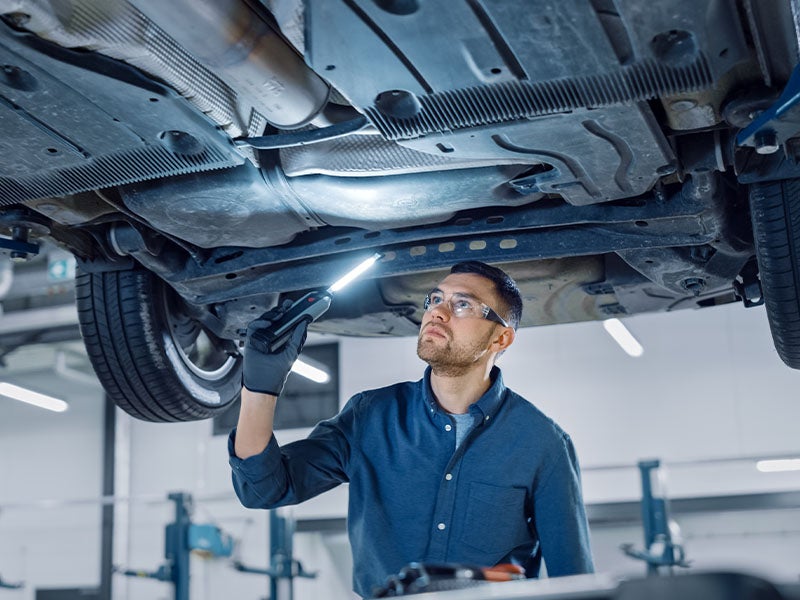 McCarthy Collision Center in Olathe KS service technician looking under car